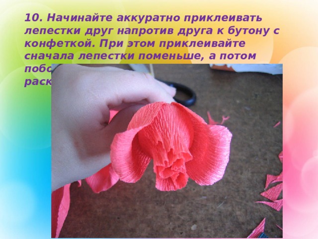 10. Начинайте аккуратно приклеивать лепестки друг напротив друга к бутону с конфеткой. При этом приклеивайте сначала лепестки поменьше, а потом побольше. Так вы имитируете раскрывающий цветок.  